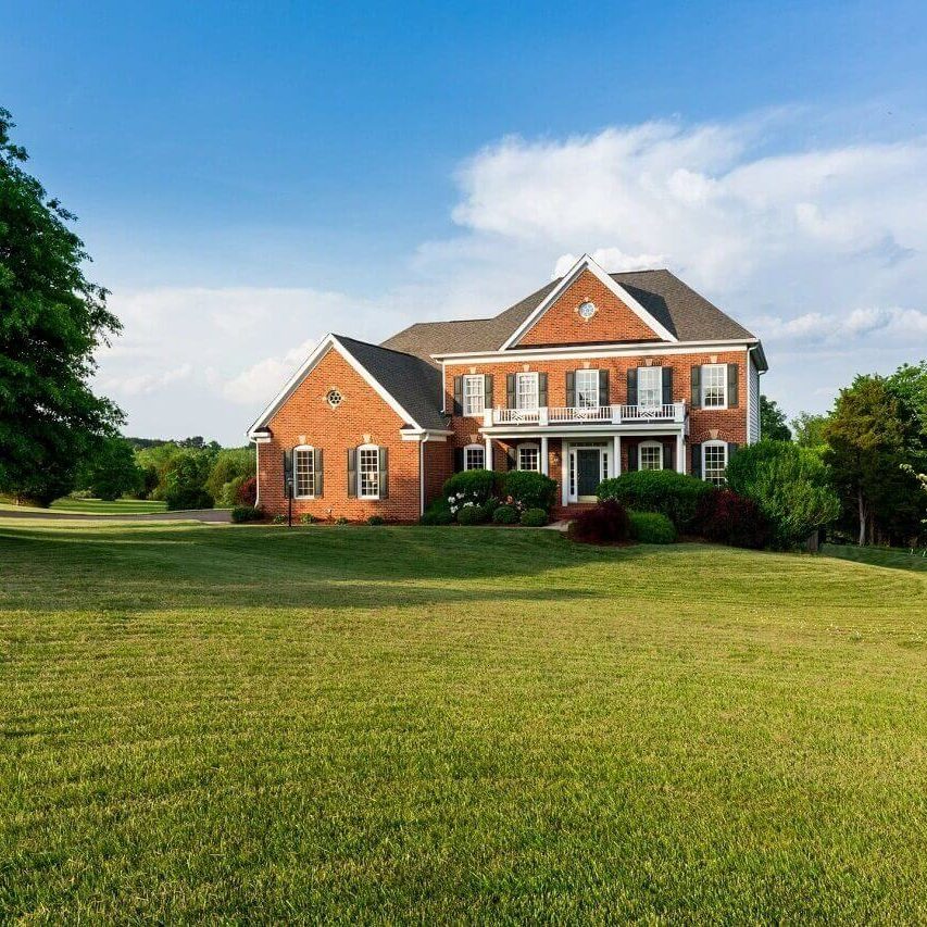 A large brick house sitting on top of a green field.